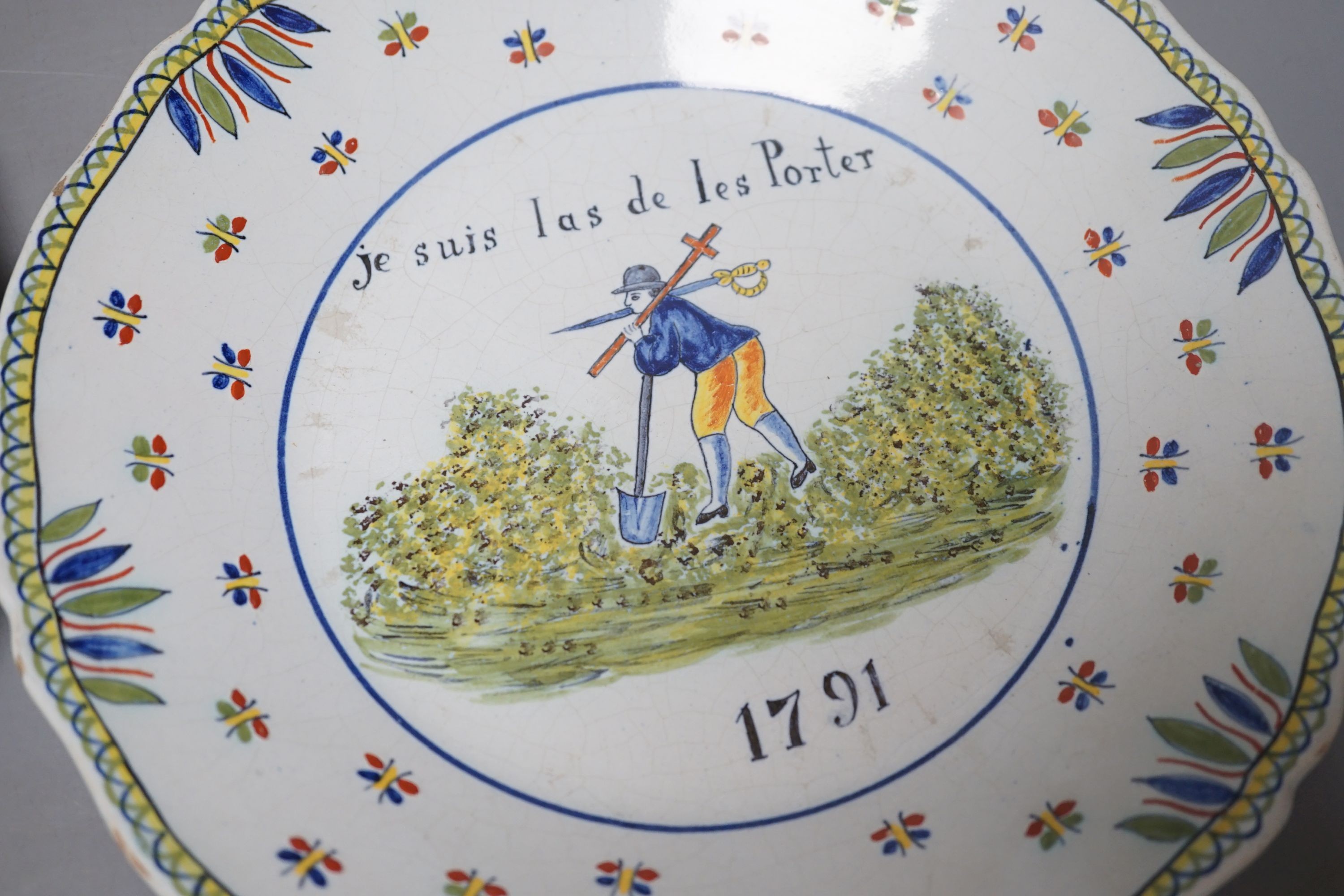 A pair of French faience plates - ‘la nation’, 1790, and ‘je suis las de les Porter’, 1791 - 24cm diameter